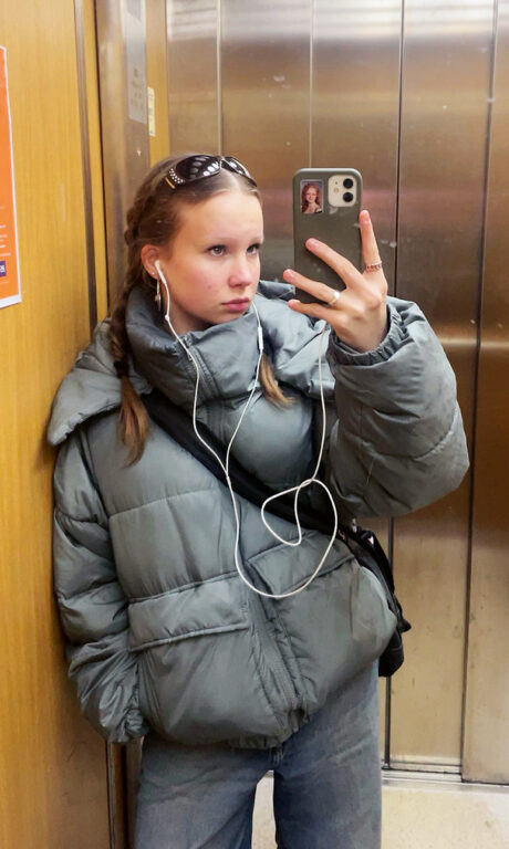 Nuori nainen ottaa itsestään kuvan hissin peilin kautta.