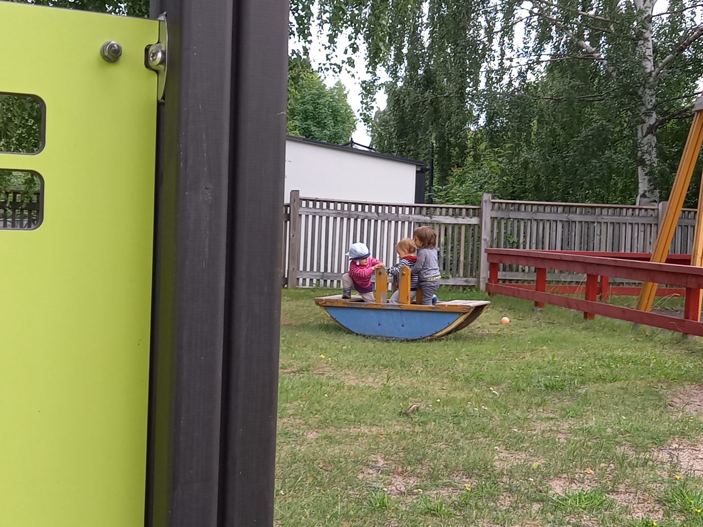 Kolme lasta keinulaudalla.