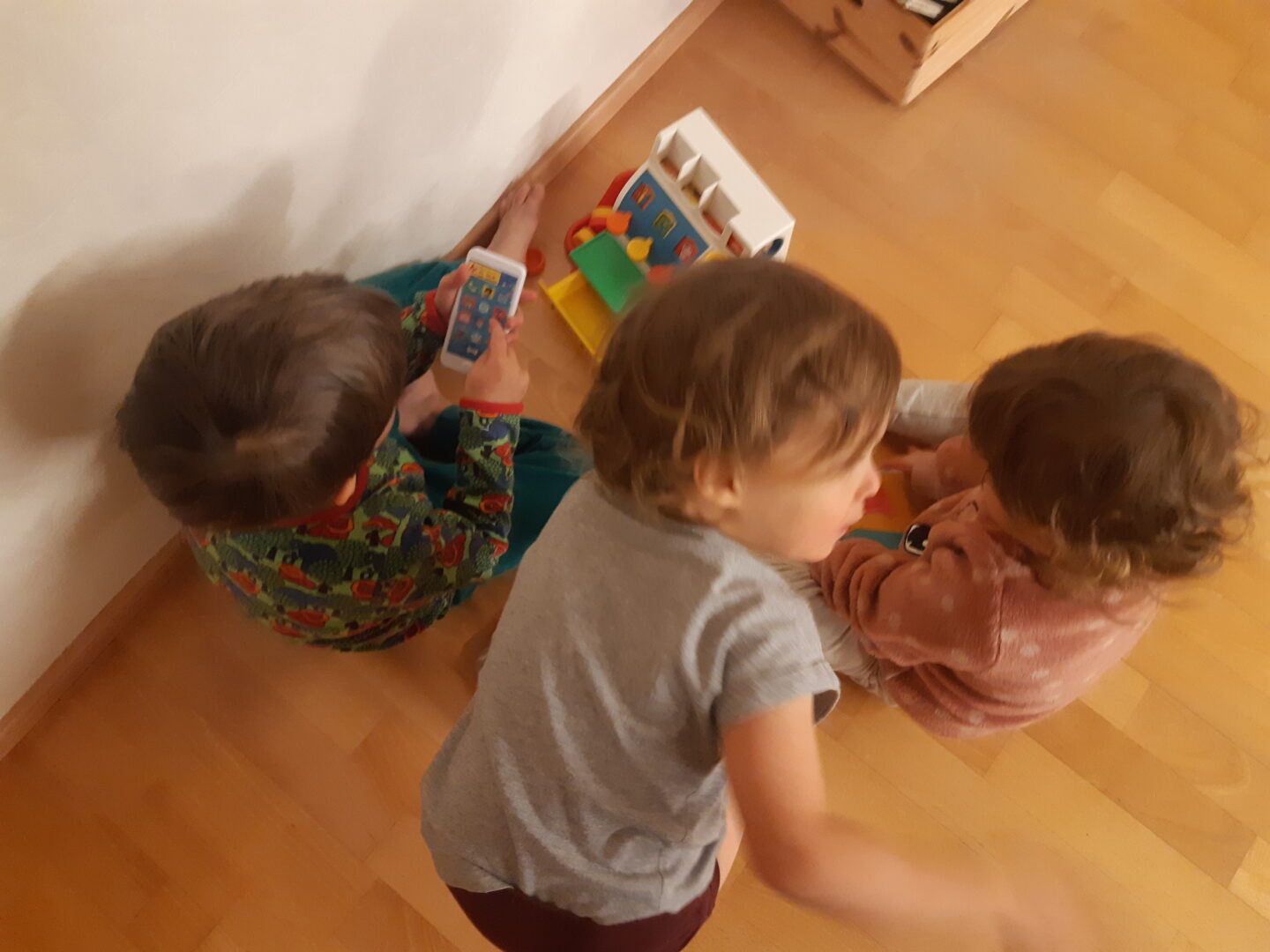 Kolme lasta leikkii kassakonelelulla.