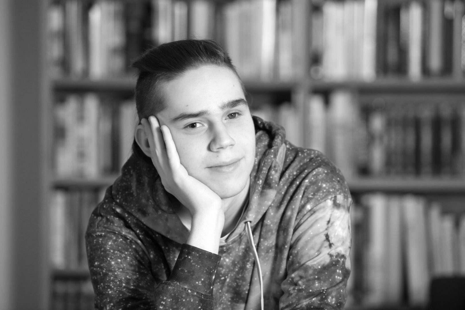 Lapsen Maailman nuorin kolumnisti Atte Ahokas katsoo kameraan päin ja nojaa toiseen käteensä. Kuva on mustavalkoinen.