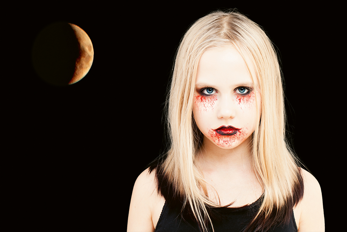 Kuvassa vampyyriksi pukeutunut tyttö. Tausta on musta, jossa on keltainen kuunsirppi.
