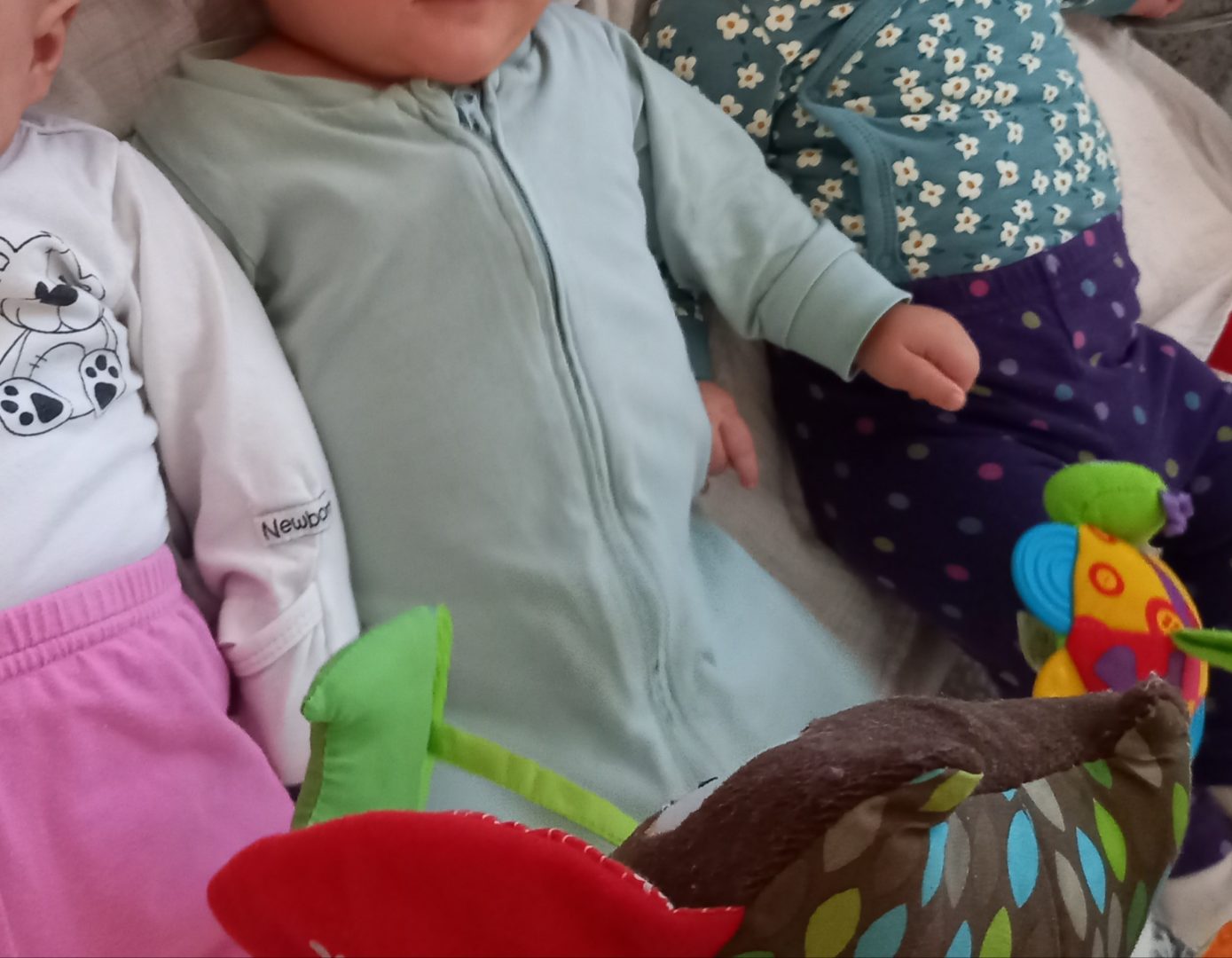 Kolme vauvaa köllöttelee vierekkäin. Kasvoja ei näy.