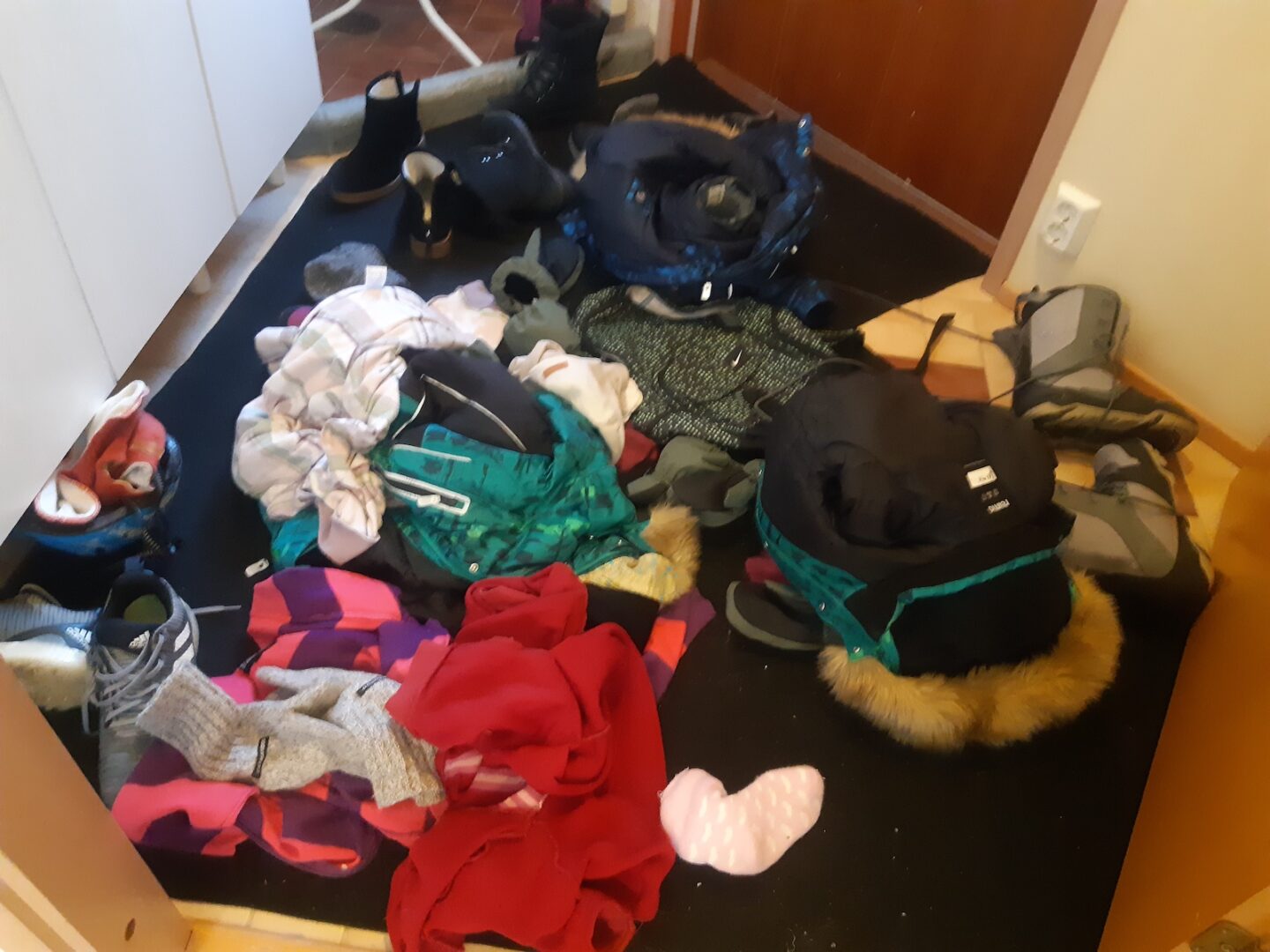 Eteisen lattia vaatteiden ja kenkien peitossa.