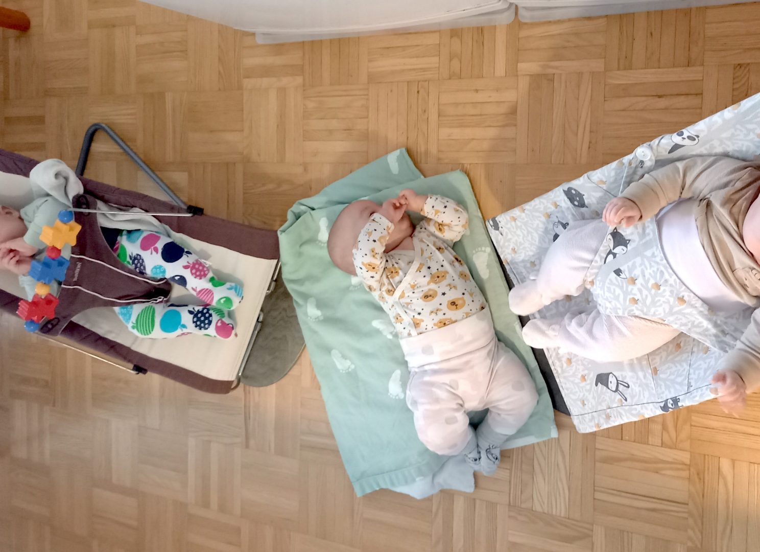 Kolme vauvaa sittereissä ja lattialla.