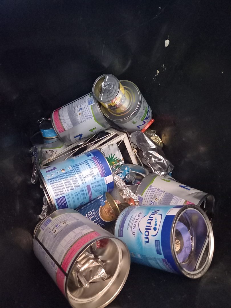 Tyhjiä maidonkorviketölkkejä metallinkeräysastiassa.