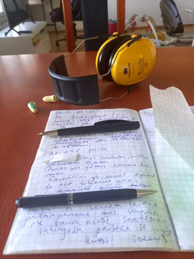 Viestivihko ja taka-alalla kuulosuojaimet ja korvatulpat.