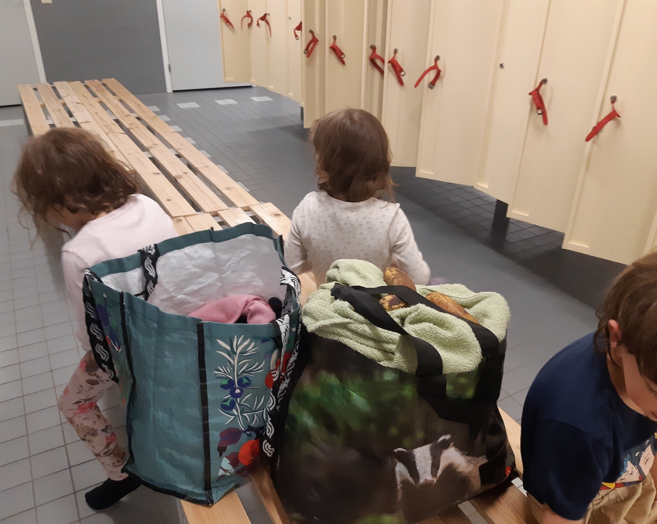 Kolmoset uimahallin pukuhuoneessa pukeutumassa.