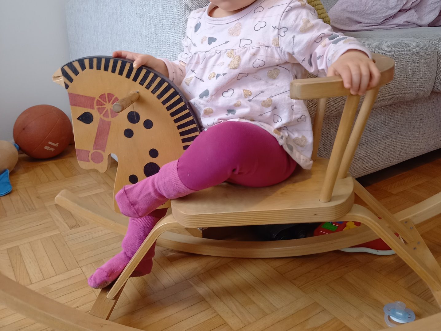 Lapsi keinuhevosen selässä, kasvot eivät näy.