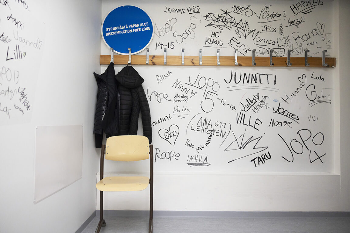 Kuva eteisestä, jonka seinä on täynnä nimikirjotuksia.