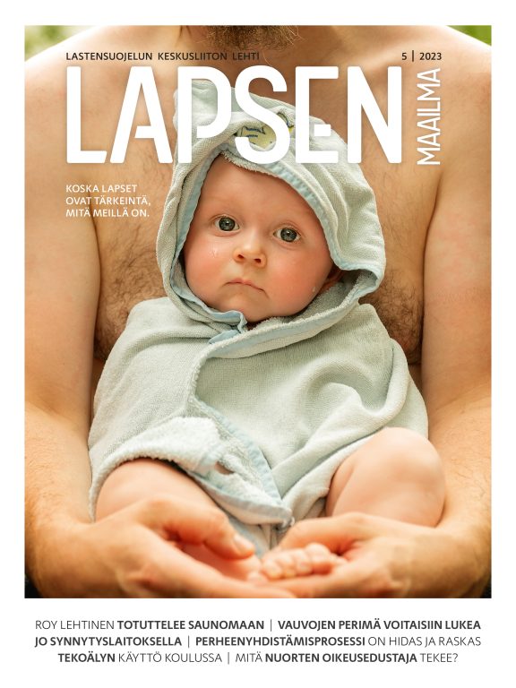Lapsen Maailma 5/2023 kansi, jossa on Isänsä sylissä oleva pieni vauva käärittynä vaaleanvihreään pyyhkeeseen