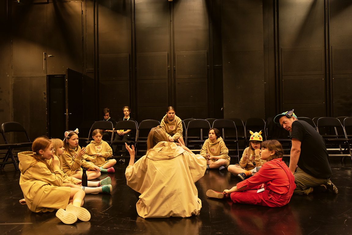 Ryhmä istuu teatterin lavalla.