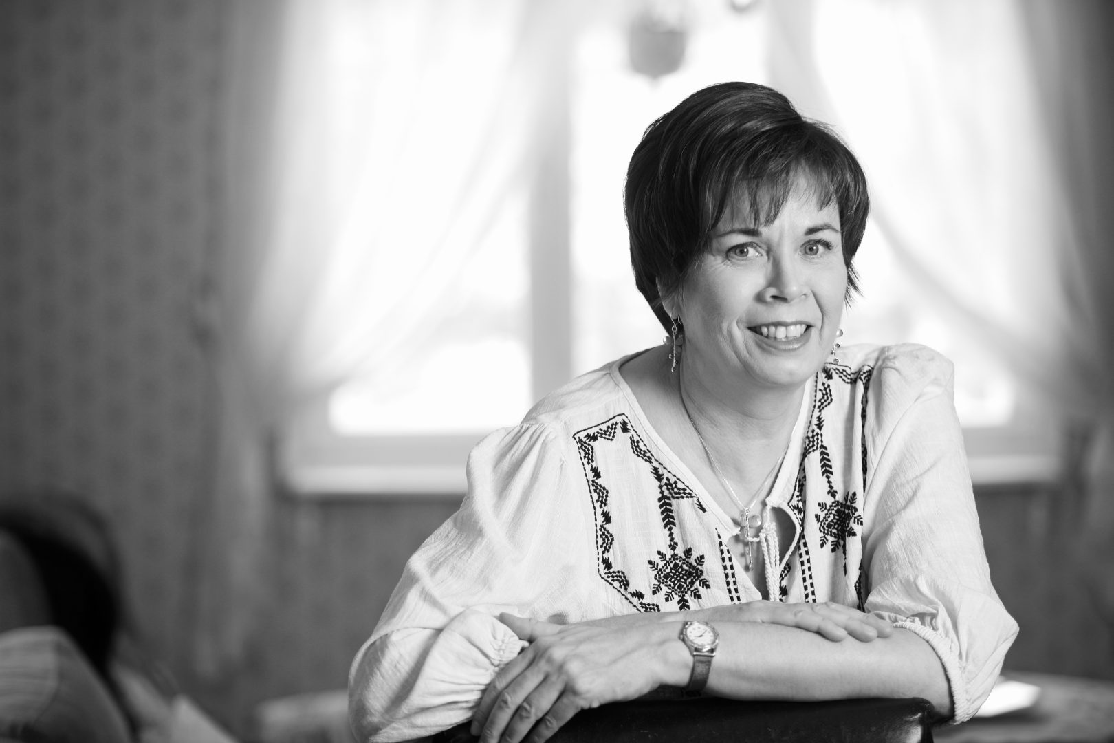 Päivi Alasalmi katsoo kameraan päin hymyillen mustavalkoisessa kuvassa.