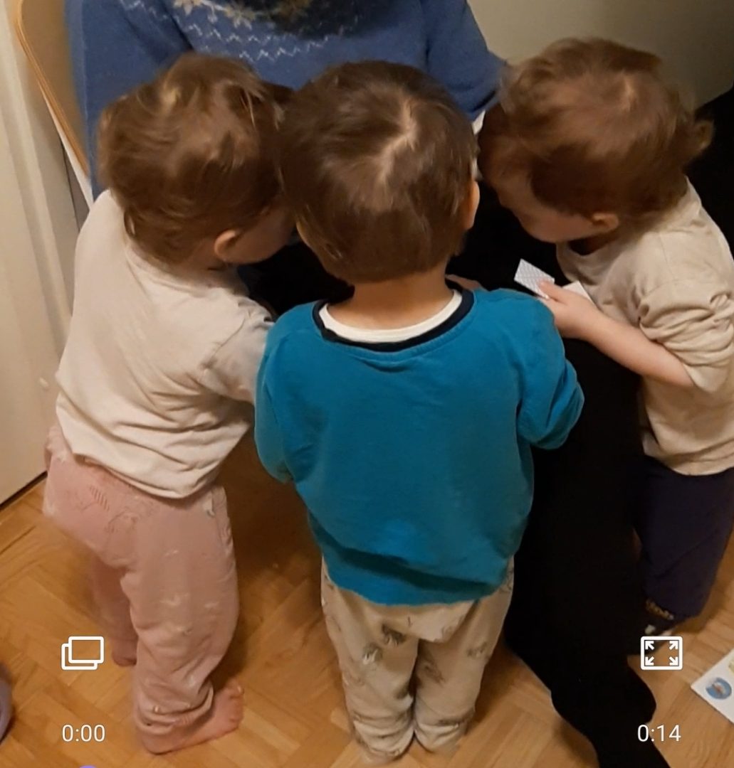 Kolme lasta kumartuneena aikuisen pariin.