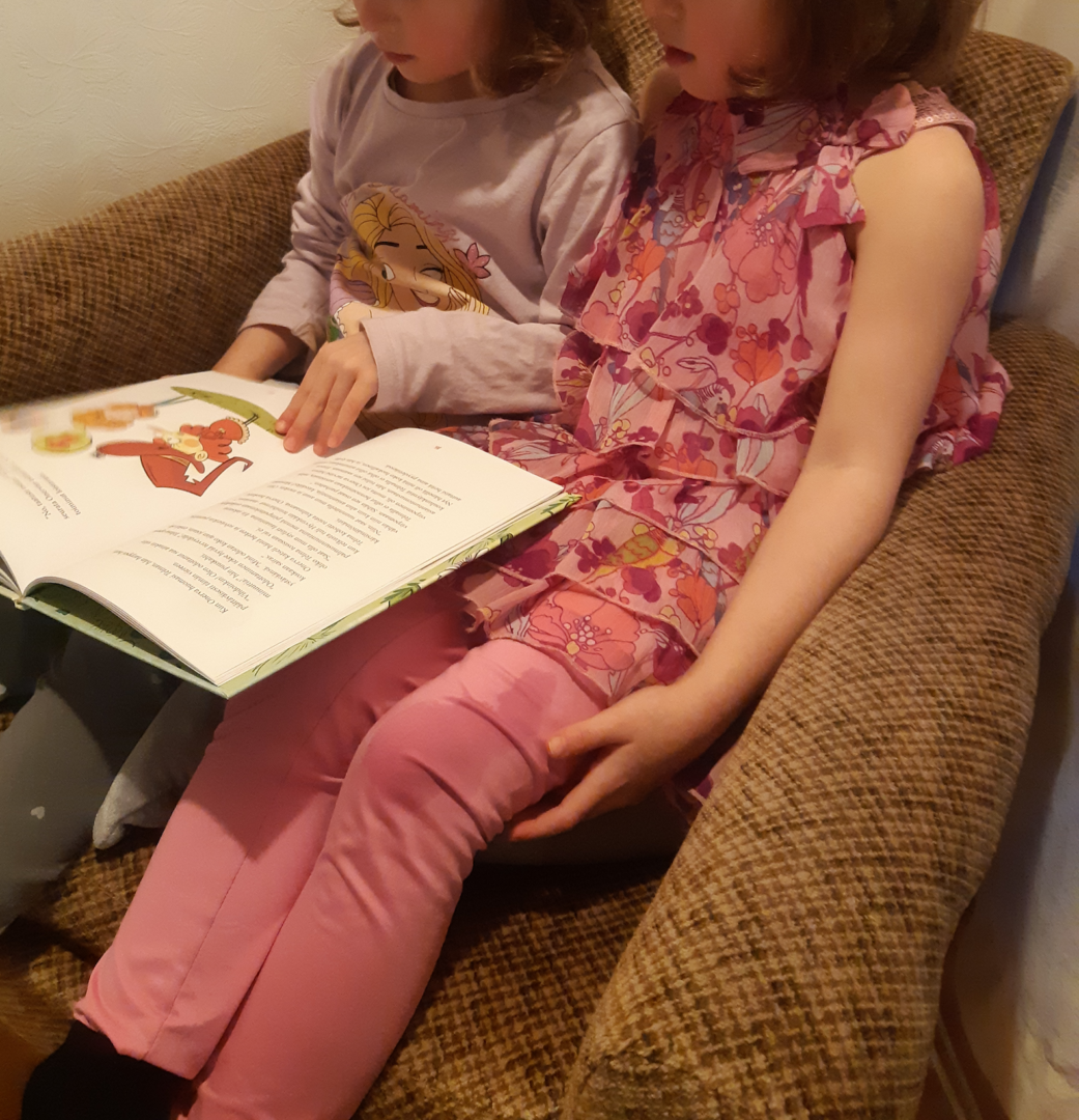 Kaksi lasta istuu nojatuolissa lukemassa.