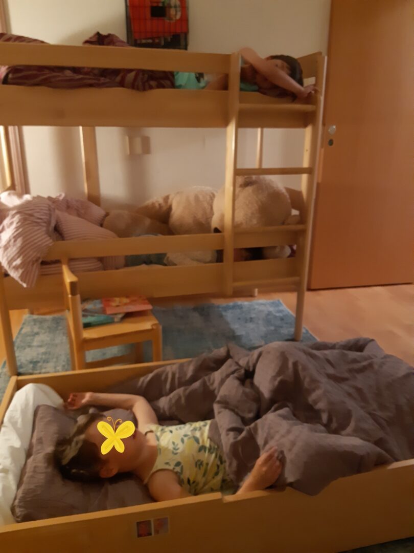 Kolme lasta kerrossängyssä ja alalaatikossa.