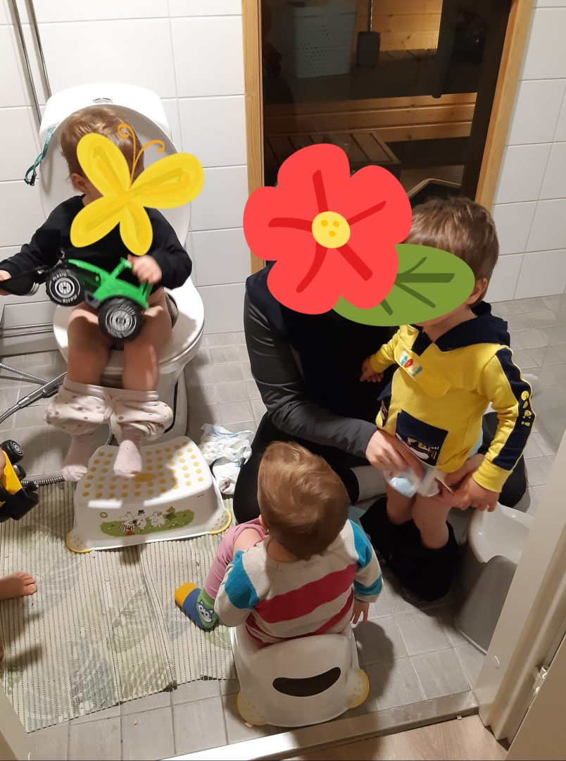 Kylpyhuoneessa kolme taaperoa ja äiti pottailemassa, kasvot peitetty.
