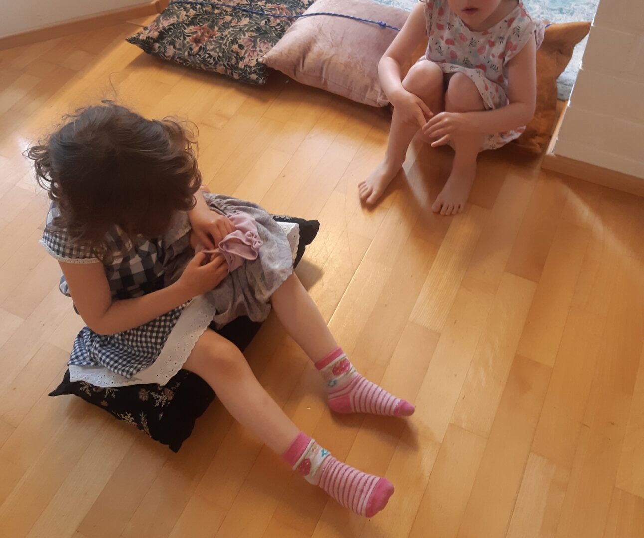Kaksi lasta istuu lattialla leikkimässä.
