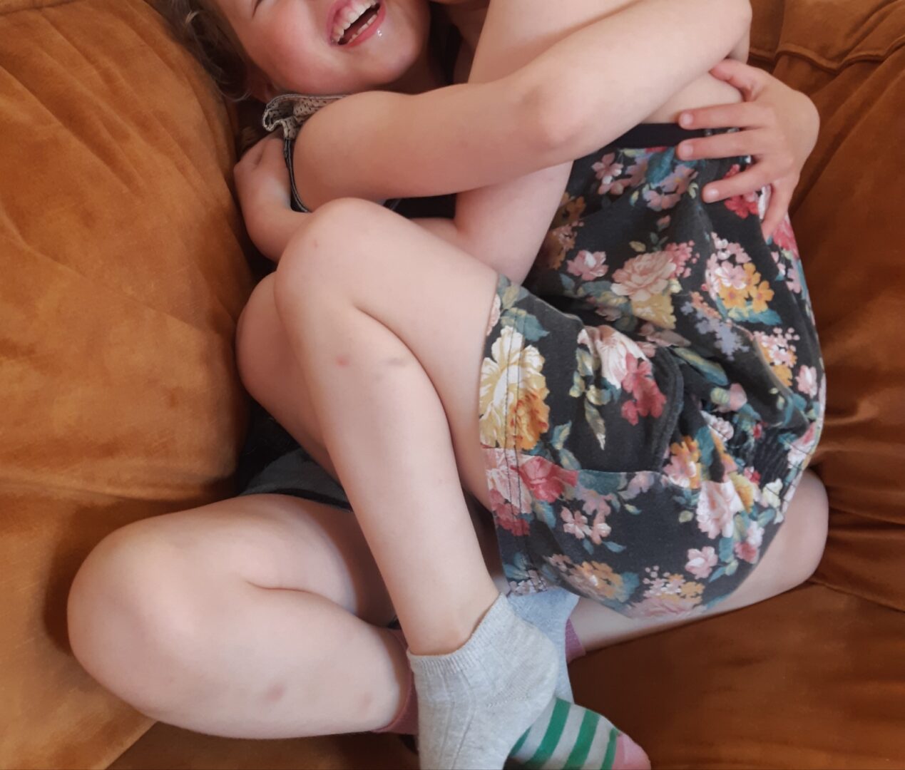 Kaksi lasta sohvalla sylikkäin.