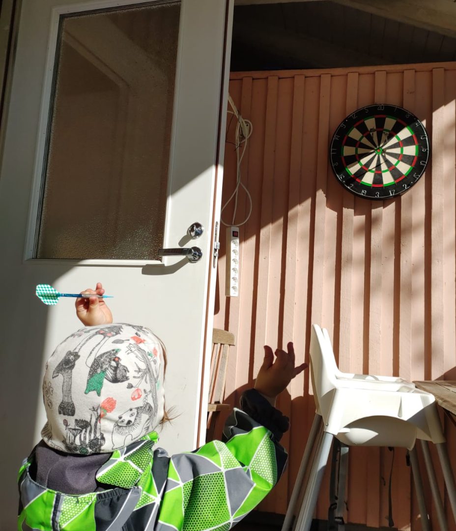 Lapsi takaapäin kuvattuna tikka kädessään. Tikkataulu edessään.