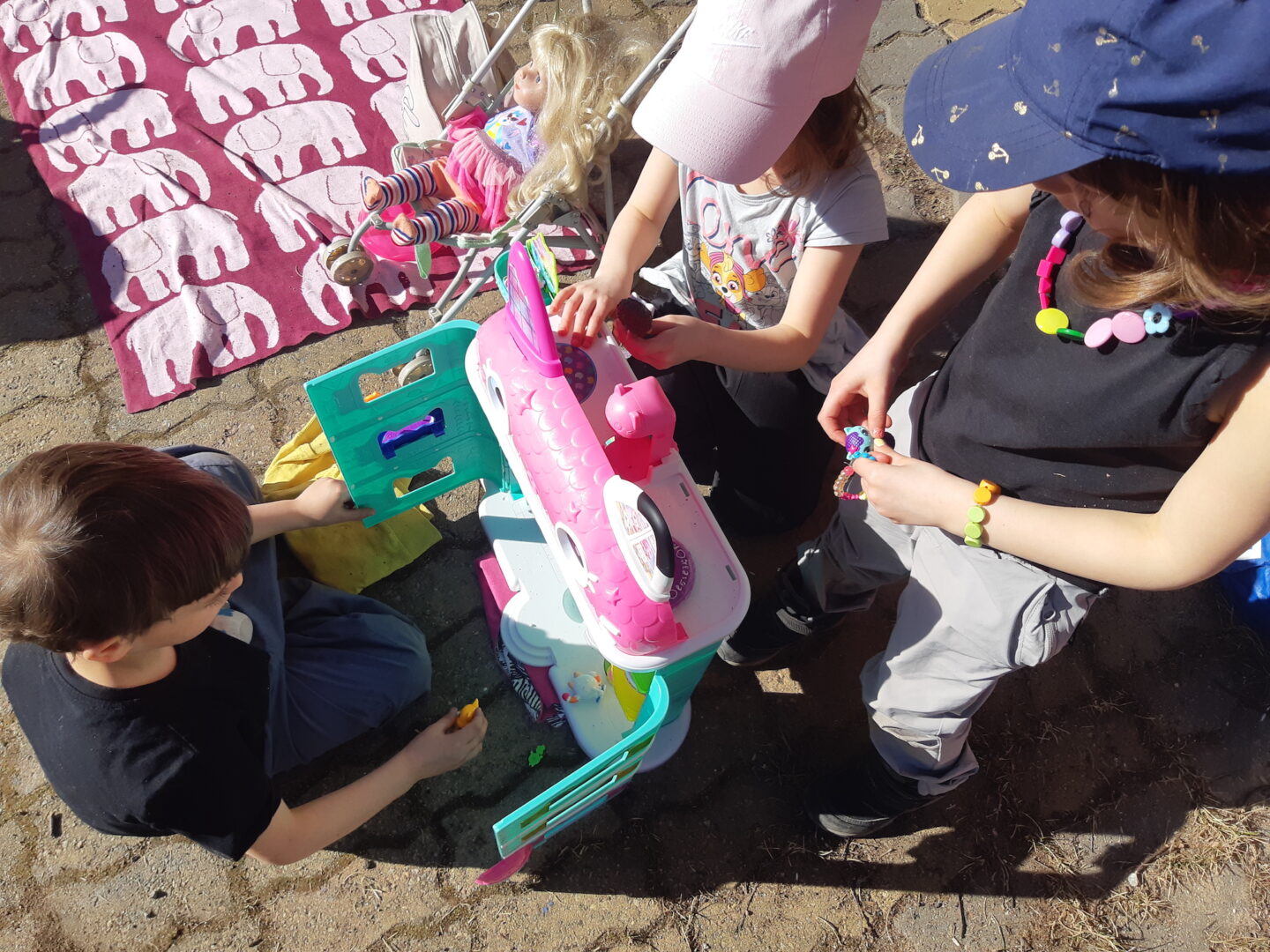 Kolmoset leikkivät ulkona nukketalolla.