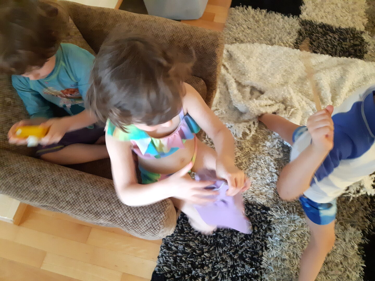 Kolme lasta nojatuolissa uimapuvuissaan.