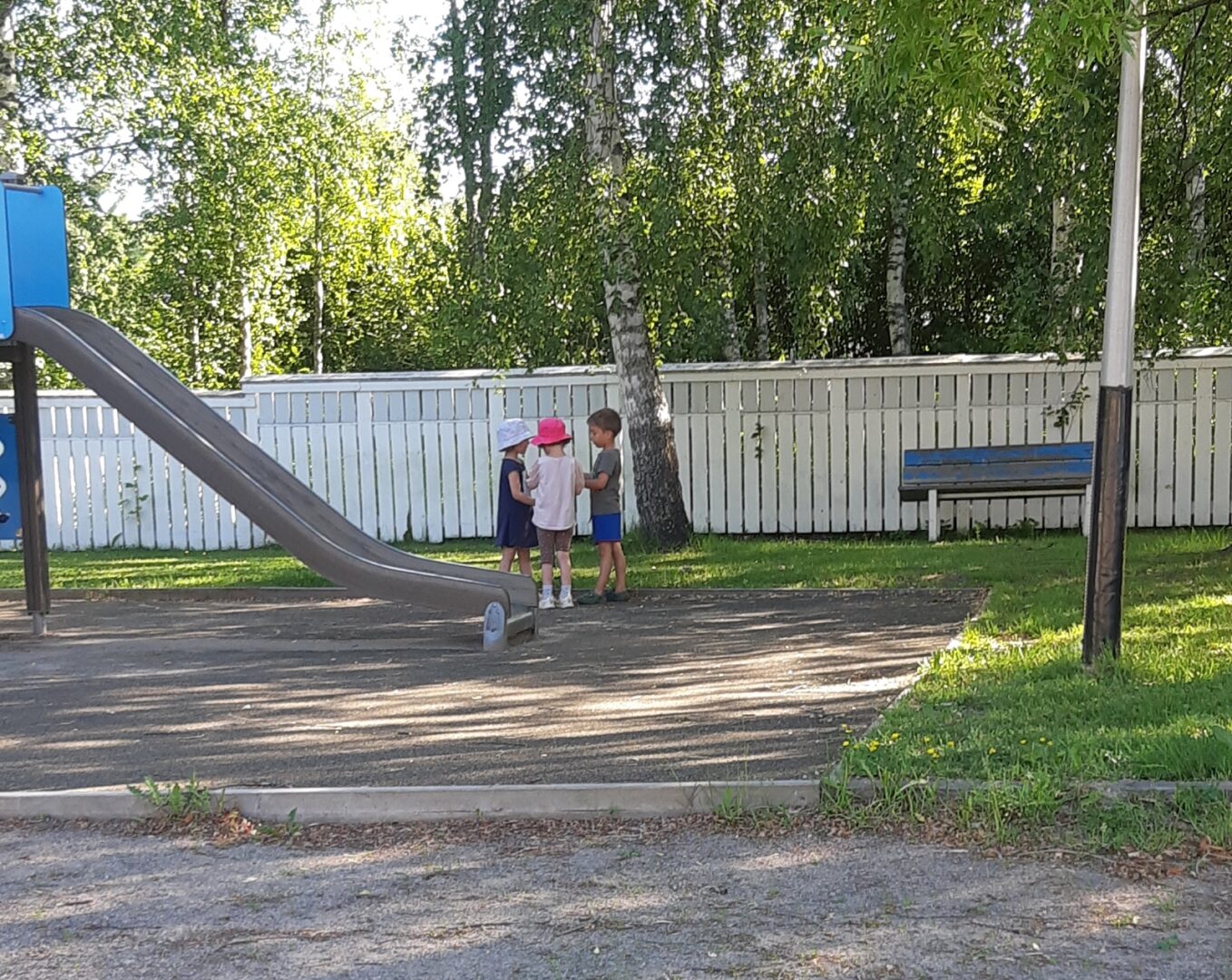 Kolme lasta leikkipaikalla.