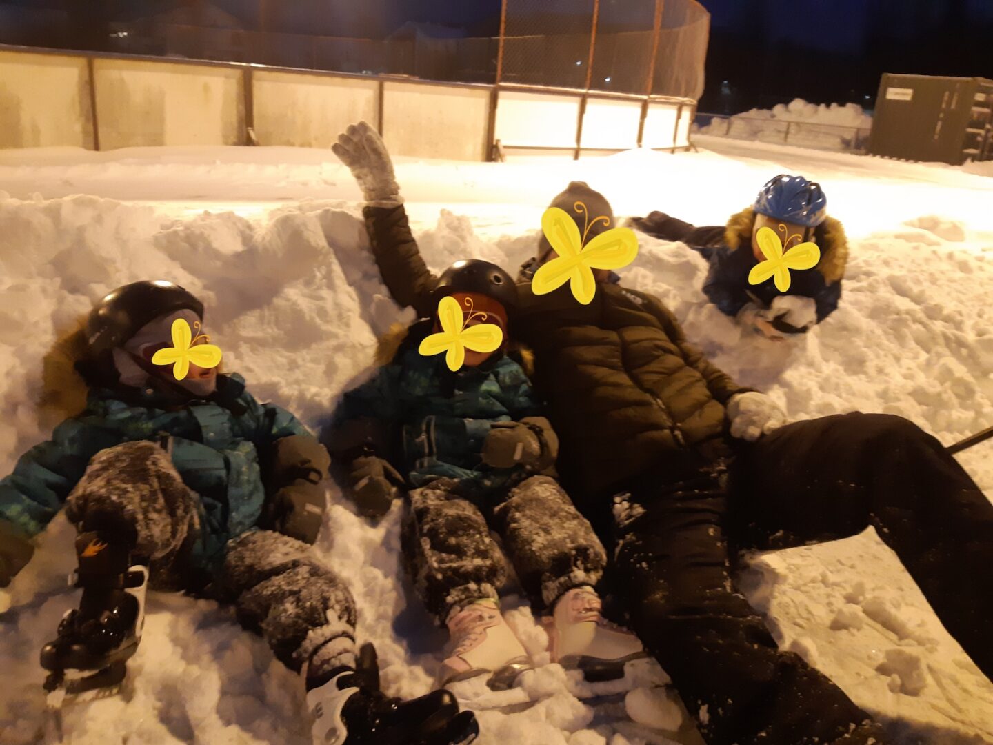 Kolme lasta ja isä luistelemassa.
