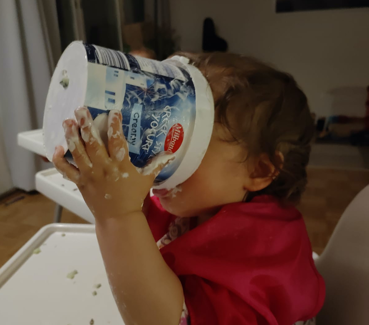 Lapsi syömässä jogurttia suoraan isosta ämpäristä.
