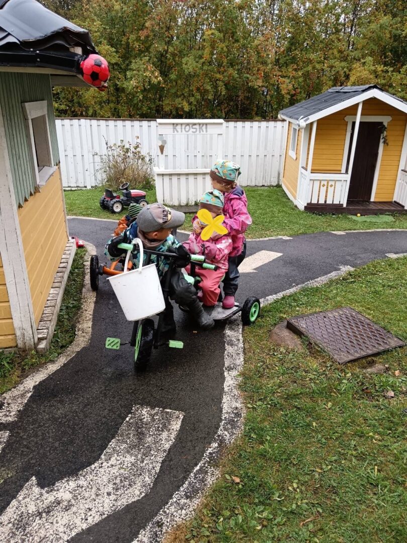 Kolme lasta polkuauton päällä.