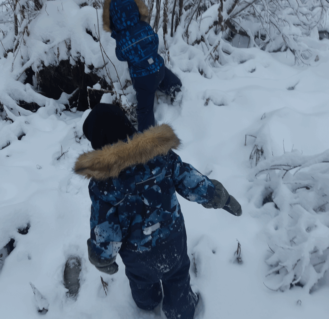 Kaksi lasta lumisessa metsässä.