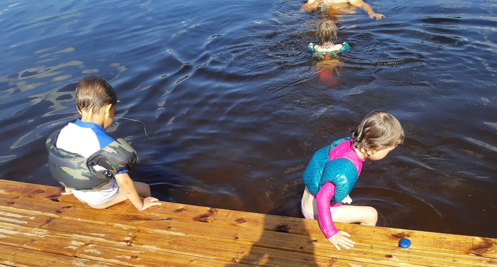 Kolme lasta ja yksi aikuinen uimassa.