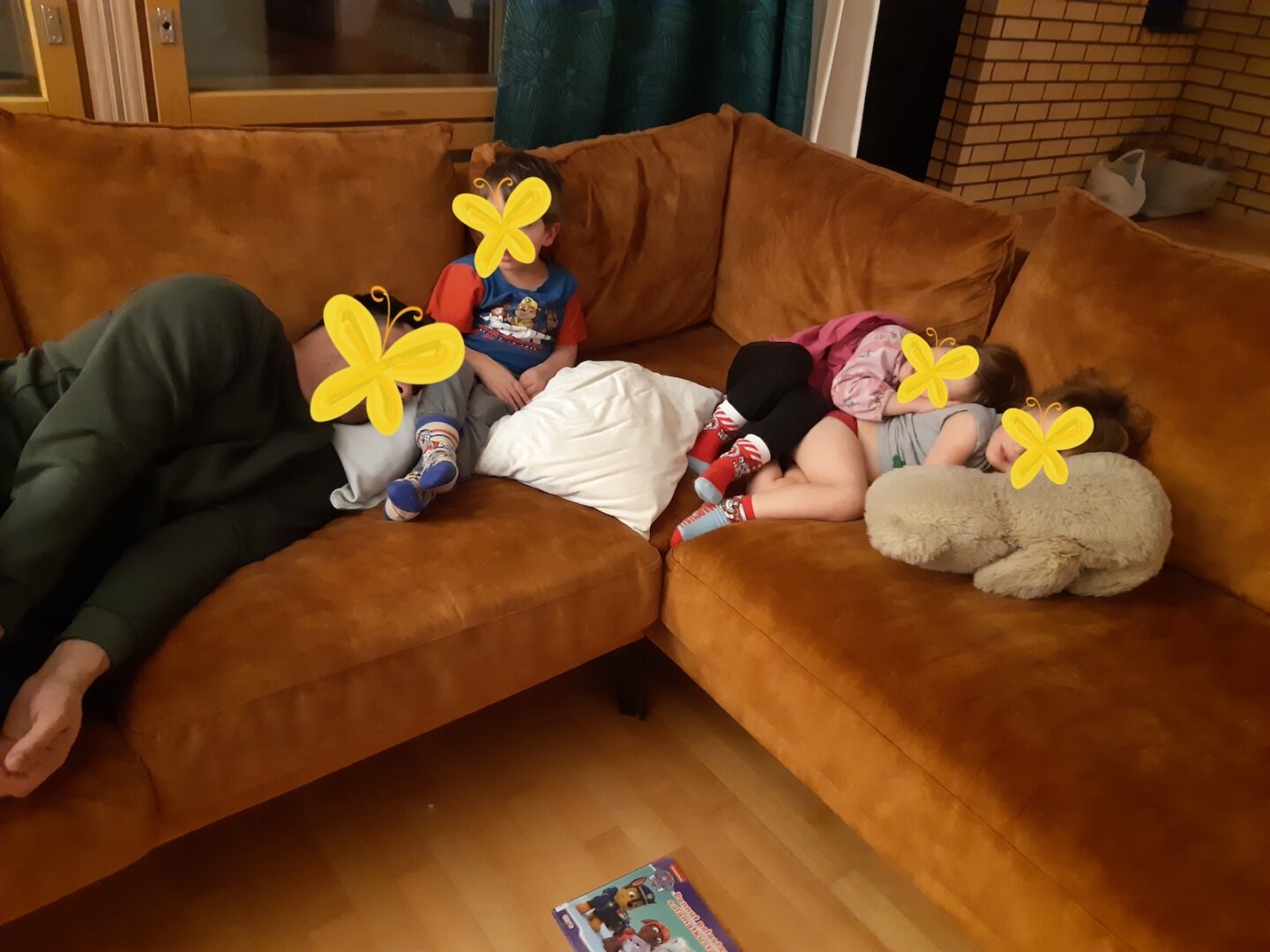 Kolme lasta ja isä makoilemassa sohvalla.