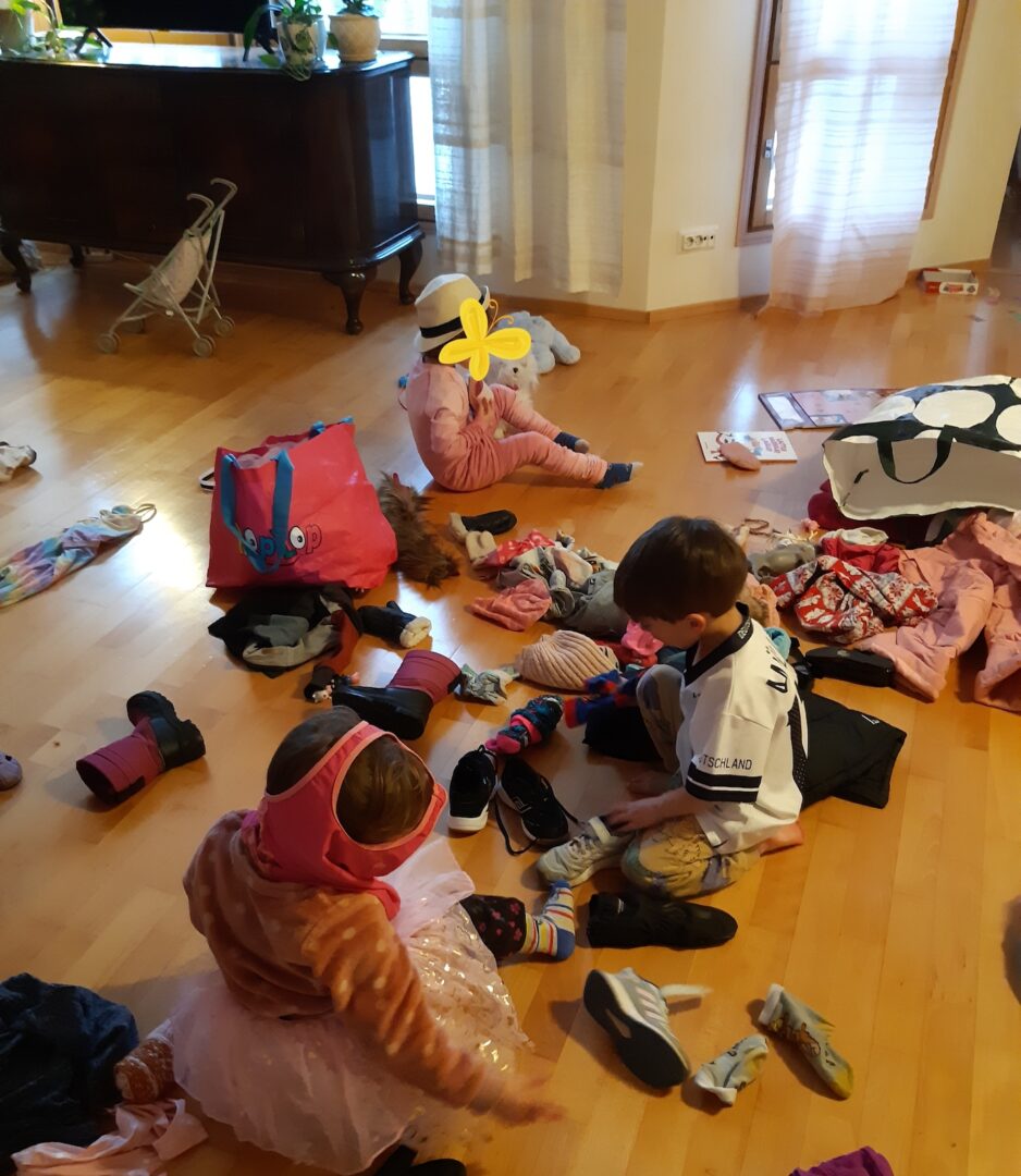 Kolme lasta vaatekasan keskellä.