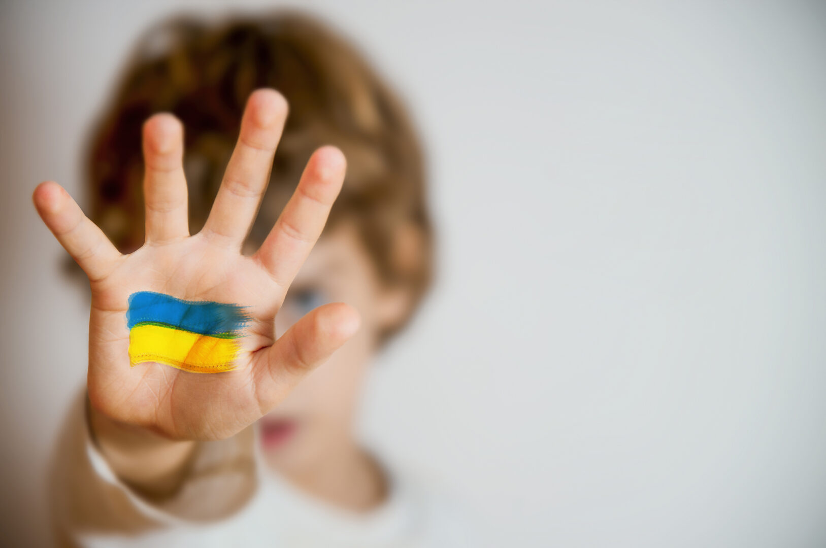 Nuori poika näyttää kameralle kättään, johon on maalattu Ukrainan lippu.
