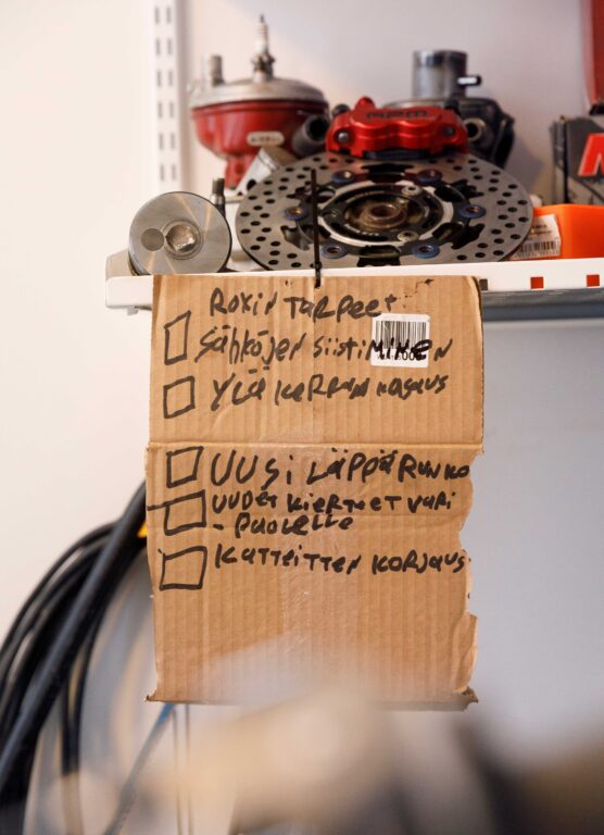 Kuvassa on pahvinpalalle kirjoitettu lista asioista, joita moposta pitää korjata.