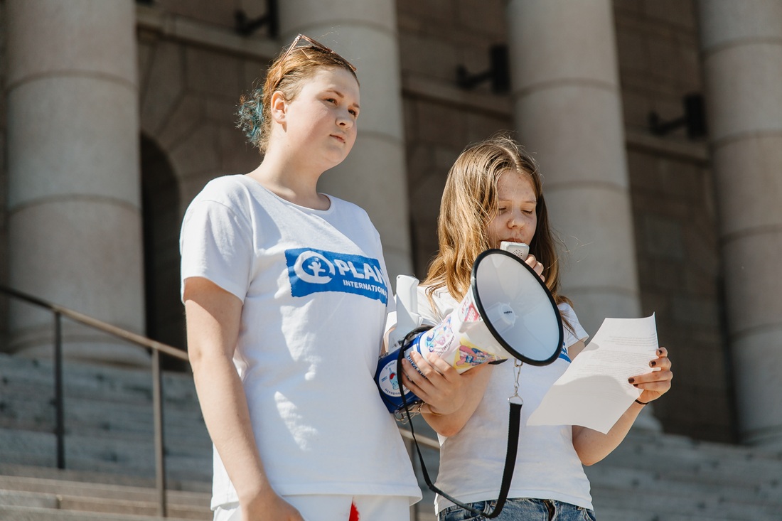 Ilona Möttölä pitämässä puhetta Eduskuntatalon edessä. Kuvassa vasemmalla Anniina Kaila.